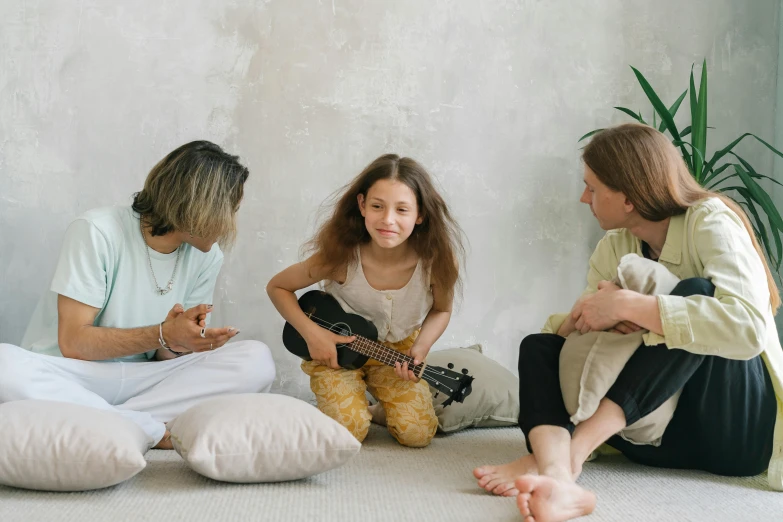 a group of people sitting on the floor playing instruments, by Emma Andijewska, pexels contest winner, with a kid, plain background, women playing guitar, 1505