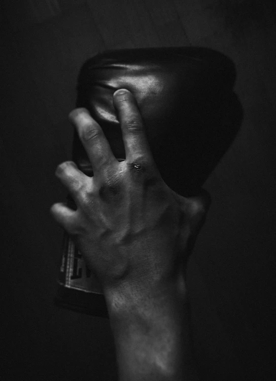 a black and white photo of a hand holding a can of soda, an album cover, inspired by Robert Mapplethorpe, unsplash, hyperrealism, drunken fist, rings, black man, leather