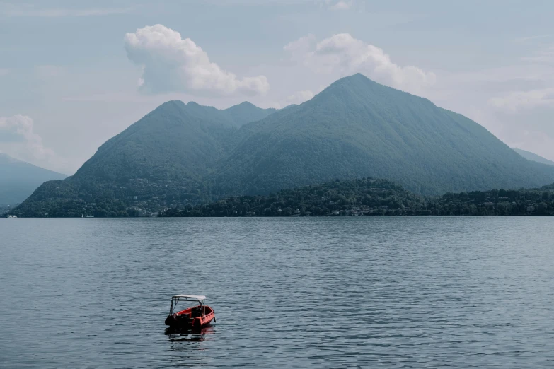 a boat floating in the middle of a lake with mountains in the background, by Julia Pishtar, pexels contest winner, mingei, vulcano, thumbnail, subtitles, 8k octan photo