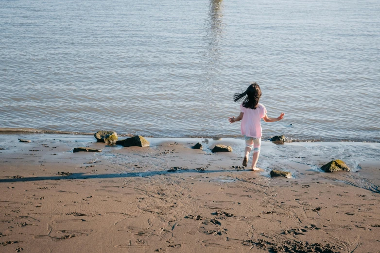 a little girl standing on top of a sandy beach, by Arabella Rankin, pexels contest winner, happening, running freely, she is walking on a river, greta thunberg, dafne keen