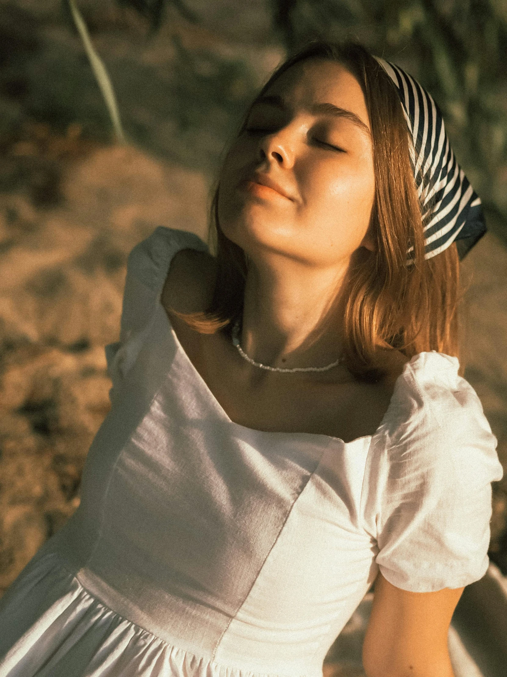 a woman in a white dress with her eyes closed, inspired by Elsa Bleda, trending on unsplash, renaissance, wearing stripe shirt, wearing a head scarf, resting on chest, high-quality photo