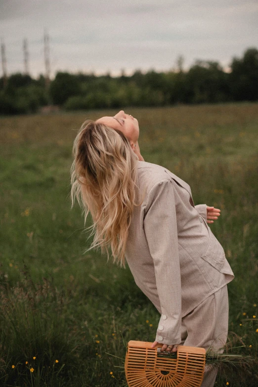 a woman standing in a field holding a basket, by Emma Andijewska, trending on unsplash, happening, blowing hair, pregnant belly, blonde flowing hair, lying dynamic pose