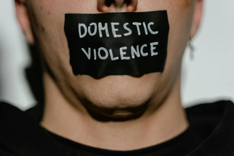 a man with a tape over his mouth that says domestic violence, by Benjamin Block, trending on pexels, renaissance, close up half body shot, 18 years old, a person standing in front of a, ribbon