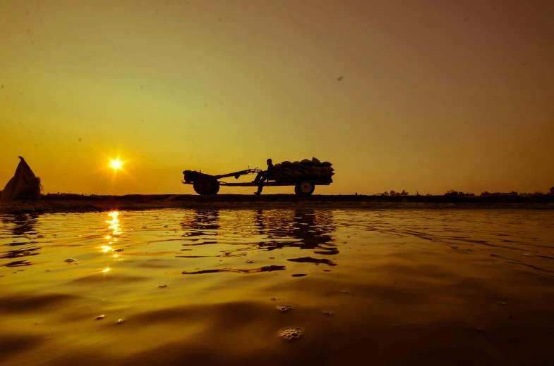 a tractor that is sitting in the water, by Matthias Weischer, pexels contest winner, low sun, myanmar, cart, thumbnail