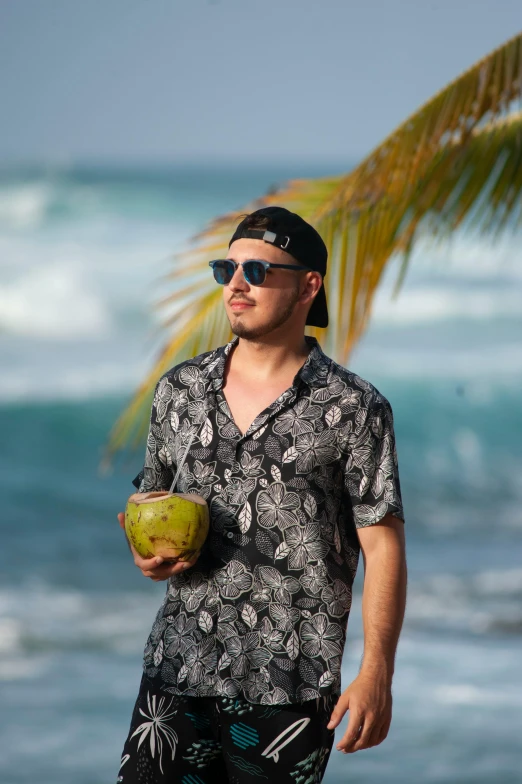 a man standing on the beach holding a coconut, by Robbie Trevino, square, wearing a shirt, profile image, pitbull