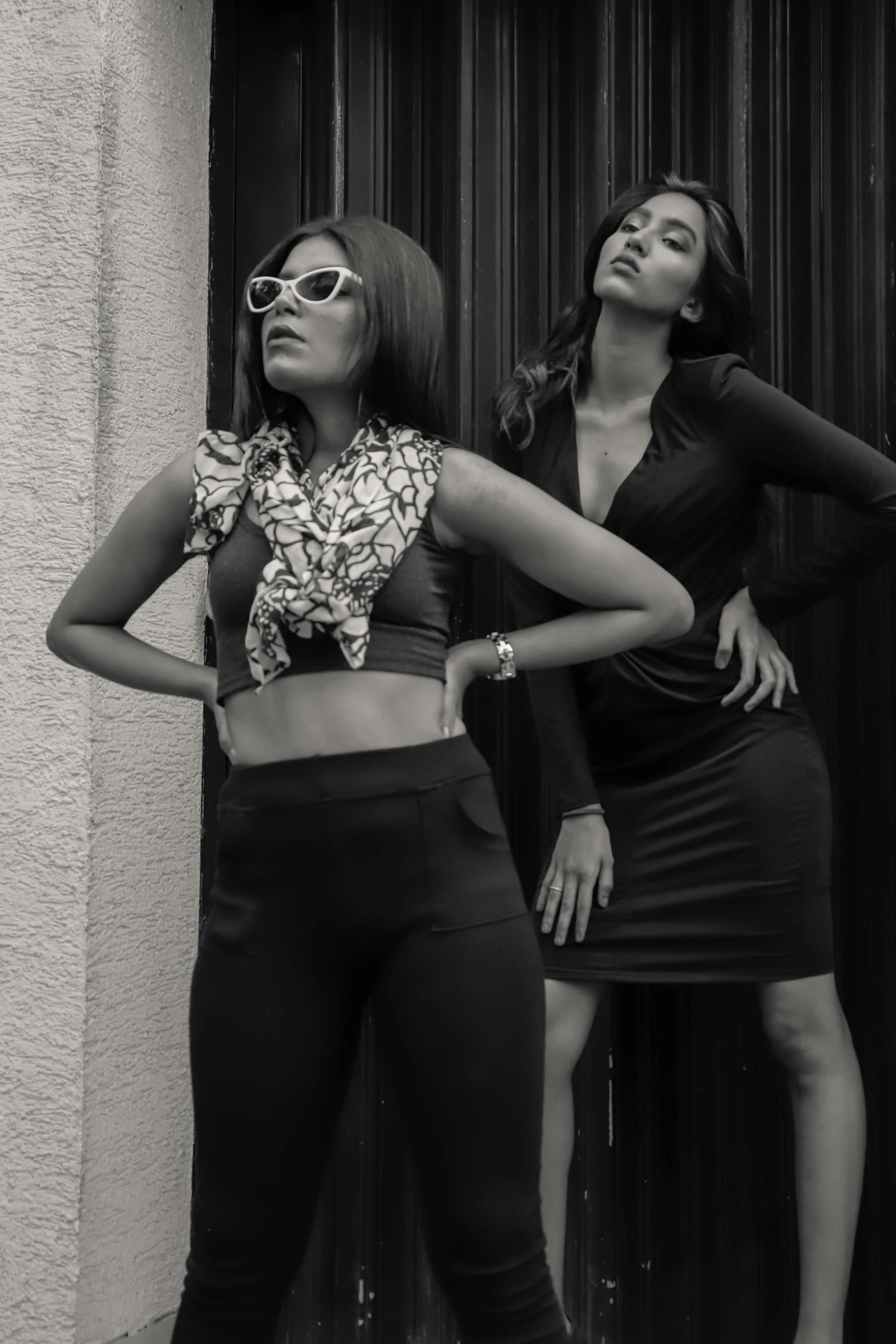 a couple of women standing next to each other, a black and white photo, trending on pexels, indian super model, doing a sassy pose, wearing tight simple clothes, ( ( theatrical ) )