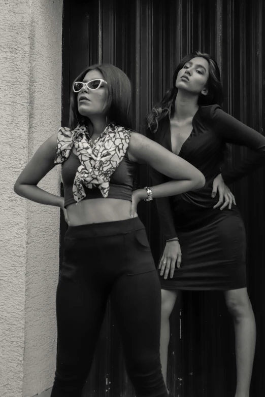 a couple of women standing next to each other, a black and white photo, trending on pexels, indian super model, doing a sassy pose, wearing tight simple clothes, ( ( theatrical ) )