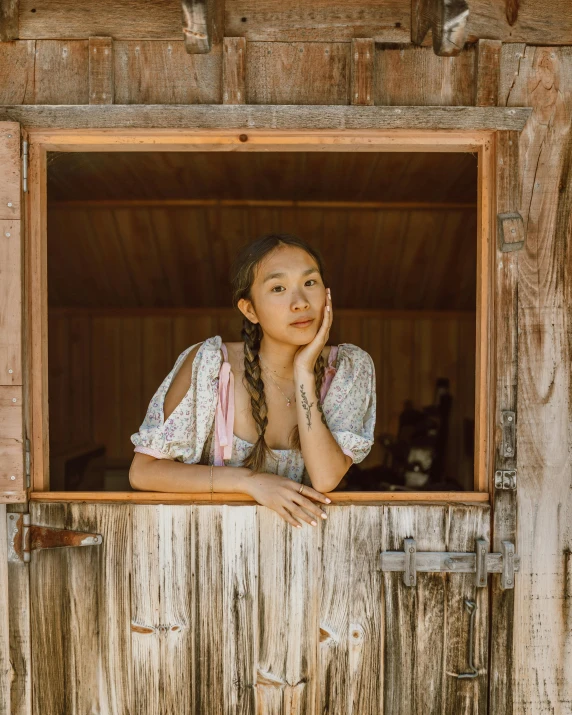 a little girl that is looking out of a window, an album cover, inspired by Ruth Jên, trending on pexels, renaissance, stood outside a wooden cabin, beautiful young asian woman, hollister ranch, lovingly looking at camera