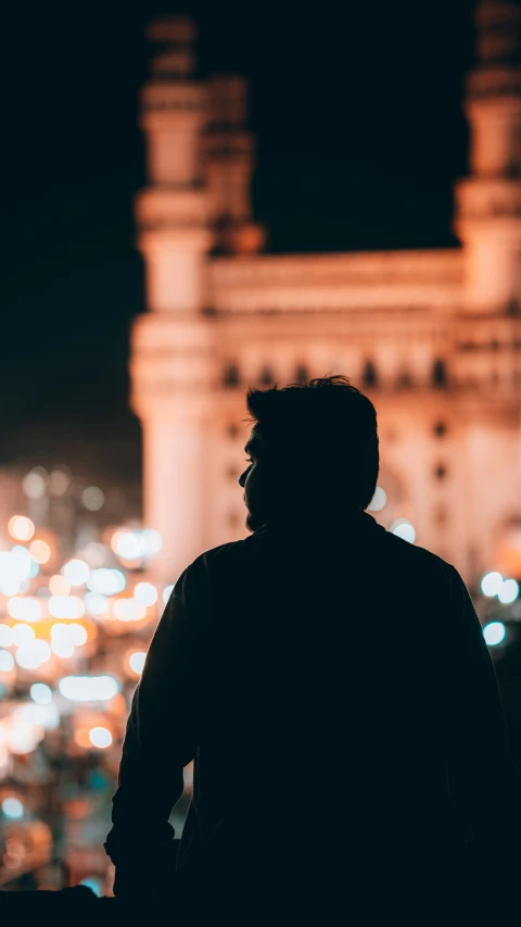 a person looking out over a city at night, pexels contest winner, arab man light beard, crowded silhouettes, profile picture, photo still of behind view