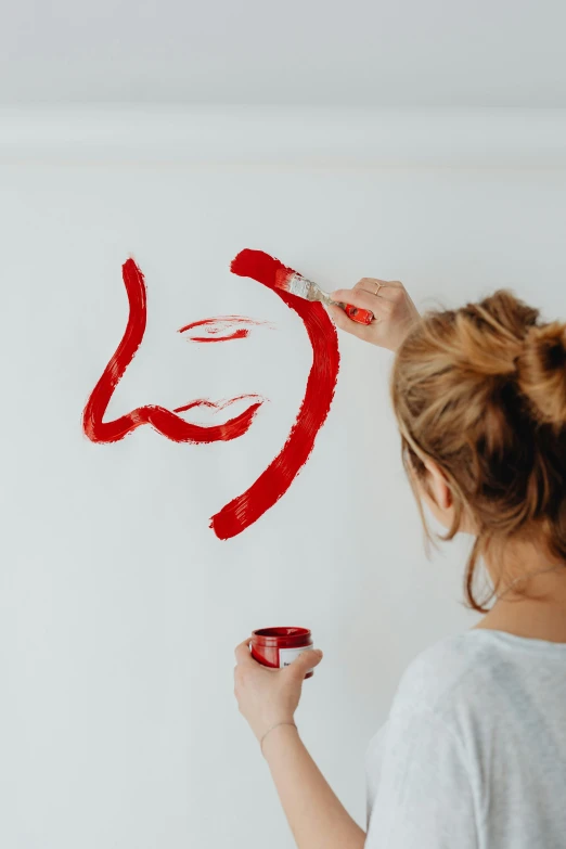 a woman is painting on a wall with red paint, a minimalist painting, by Julia Pishtar, trending on pexels, charming expression gesicht, on white, making the best smug smile, trending on artstion