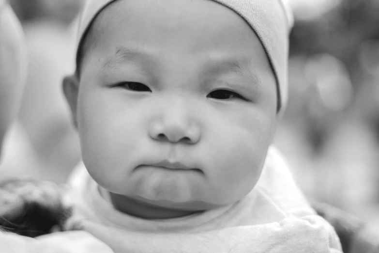 a close up of a person holding a baby, a black and white photo, unsplash, mingei, wan adorable korean face, square nose, proud serious expression, monochrome:-2