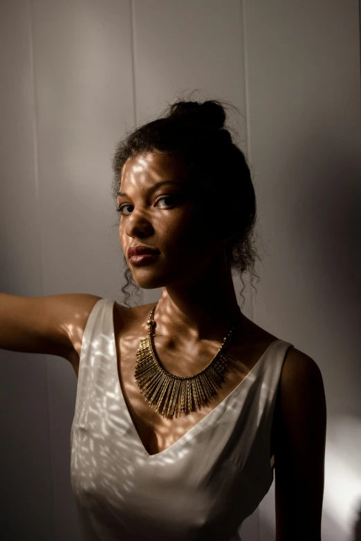 a woman in a white dress poses for a picture, inspired by Esaias Boursse, pexels contest winner, wears a egyptian ankh necklace, well lit studio lighting, brown skinned, in a sunbeam