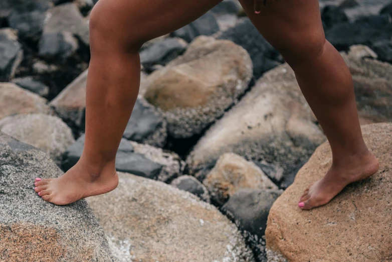 a woman standing on top of a rock next to a body of water, pexels contest winner, realism, detailed legs, kids playing at the beach, athletic muscle tone, crawling