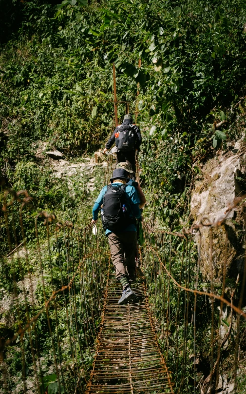 a man walking across a wooden suspension bridge, an album cover, by Jessie Algie, pexels, sumatraism, wearing adventure gear, nepal, thumbnail, coming down the stairs