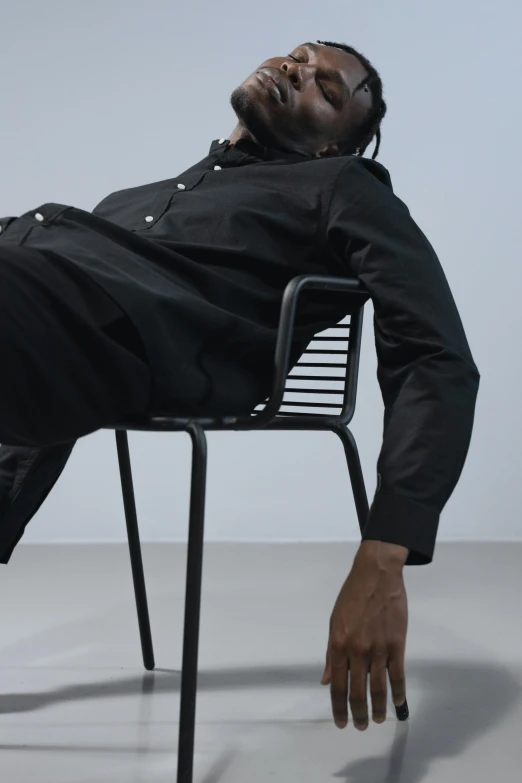 a man that is laying down on a chair, trending on unsplash, photorealism, black body, black, zoomed out full body, minimal clothing