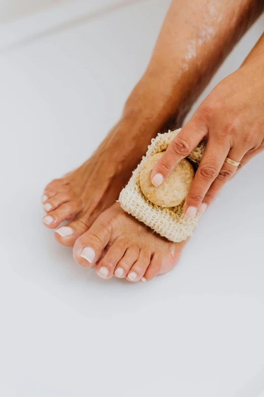 a woman scrubs her feet with a sponge, by Victorine Foot, manuka, real pearls, highly textured, light tan