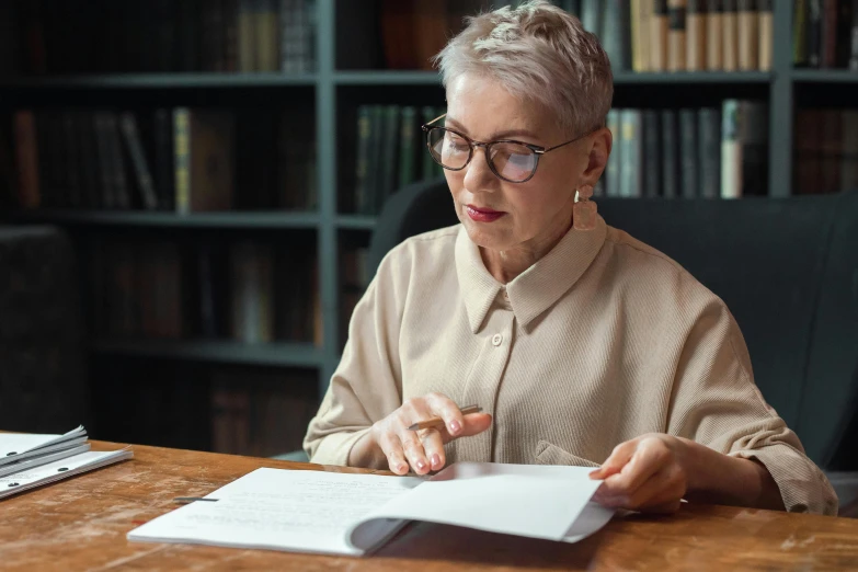 a woman sitting at a table reading a book, gray haired, professional photo, abcdefghijklmnopqrstuvwxyz, multiple stories