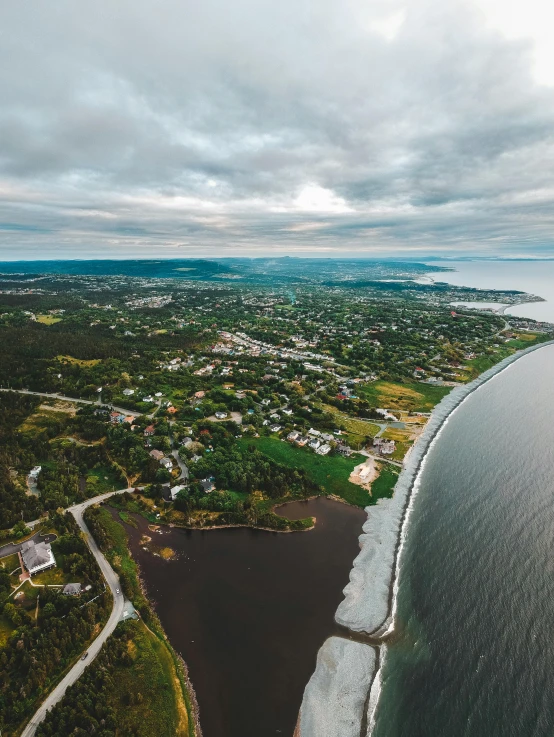 an aerial view of a large body of water, a picture, by Roar Kjernstad, pexels contest winner, small town surrounding, views to the ocean, on a cloudy day, taken on go pro hero8