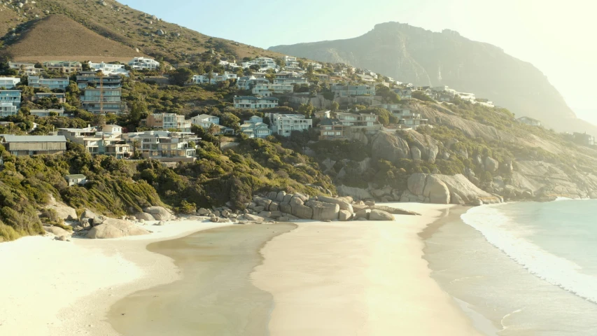 a view of a beach with a mountain in the background, white houses, award winning cinematic, elize theron, aerial