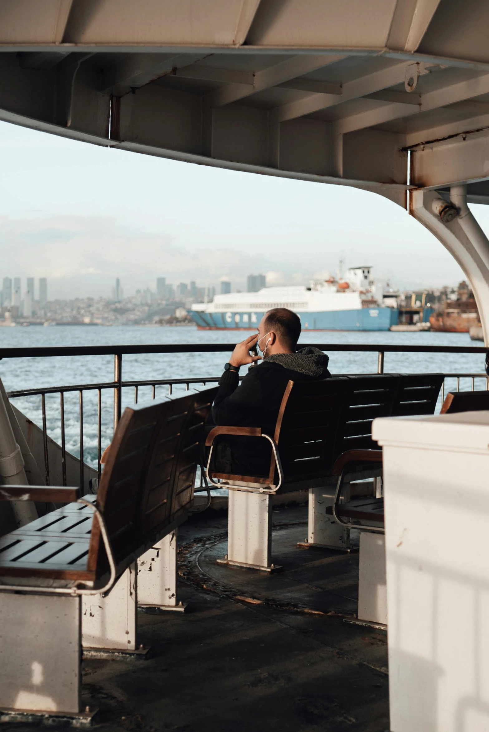 a man sitting on a bench talking on a cell phone, on the deck of a ship, the space needle, 2019 trending photo, manly