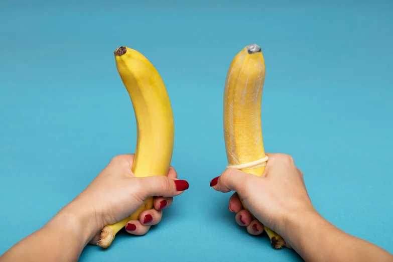 a person holding two bananas in their hands, an album cover, inspired by Sarah Lucas, unsplash, contracept, two male, implants, half blue