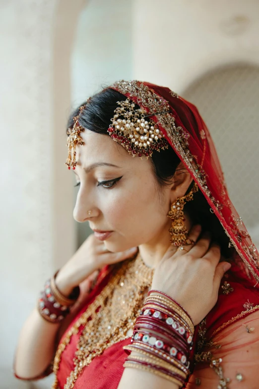 a woman in a red and gold outfit, inspired by Li Di, pexels, bride, 2 5 6 x 2 5 6 pixels, middle eastern details, contemplating