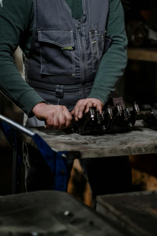 a man that is standing in front of a table, pexels contest winner, arbeitsrat für kunst, holding a wrench, engines, cast iron material, inspect in inventory image
