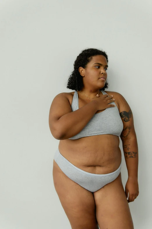 a woman in a bikini posing for a picture, by Matija Jama, trending on pexels, renaissance, her belly is fat and round, flat grey, looking off to the side, non-binary