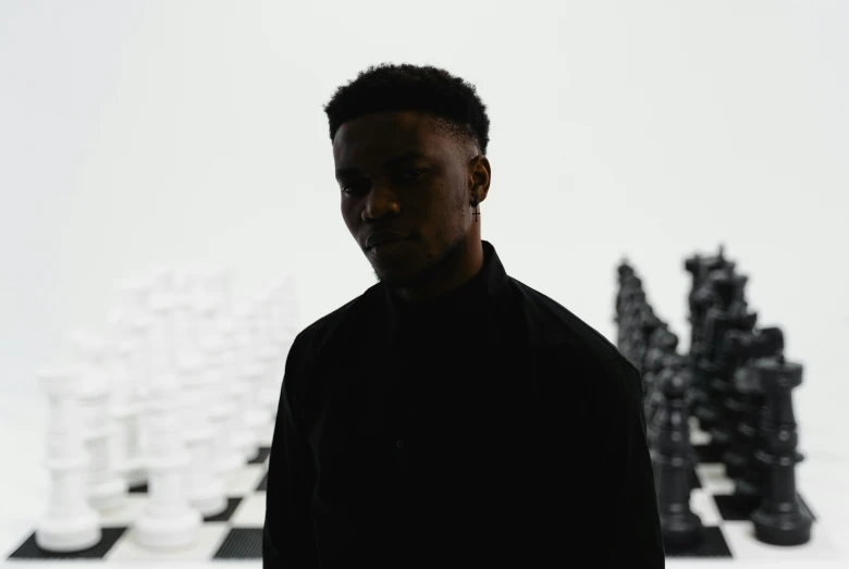 a man standing in front of a chess board, an album cover, inspired by Paul Georges, pexels contest winner, visual art, mkbhd, side profile portrait, black elon musk, highly reflective