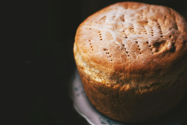 a loaf of bread sitting on top of a plate, unsplash, hurufiyya, pot, intricate texture, round-cropped, ready to eat