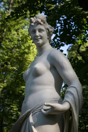 a statue in a park with trees in the background, inspired by Antonio Canova, trending on reddit, mannerism, female human torso, large hips, self - satisfied smirk, biedermeier