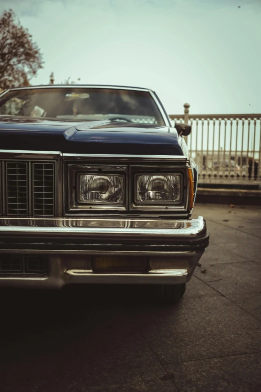 a black car parked in a parking lot, an album cover, pexels contest winner, photorealism, blue headlights, 1980 cars, lowrider style, brown
