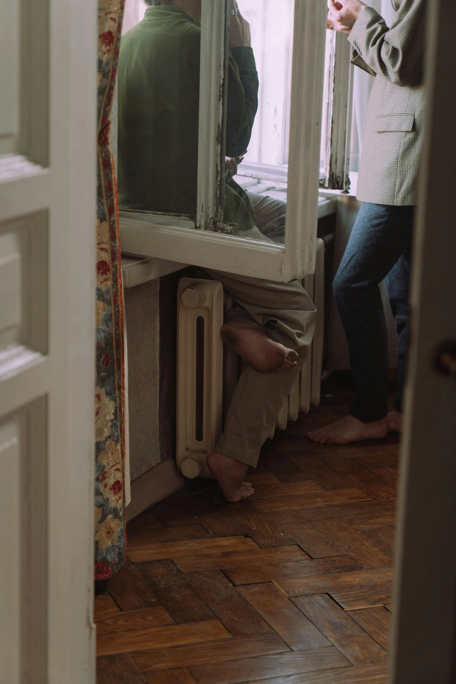 a couple of people standing in front of a window, by Elsa Bleda, hyperrealism, her foot sticking out, home video footage, radiator, 35mm —w 1920 —h 1080