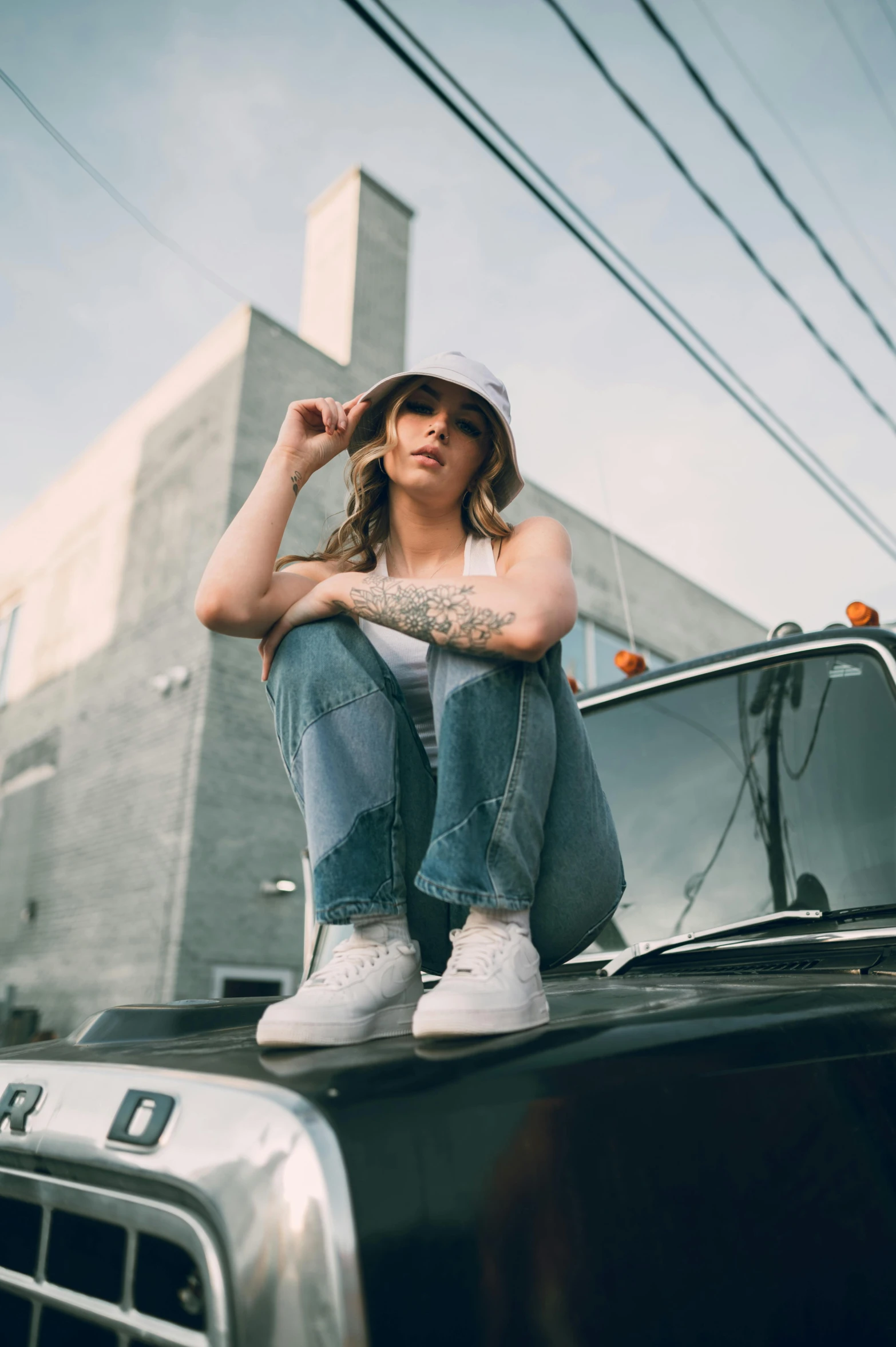 a woman sitting on the hood of a truck, a portrait, by Drew Tucker, trending on pexels, white cap, baggy jeans, felix englund, promotional image