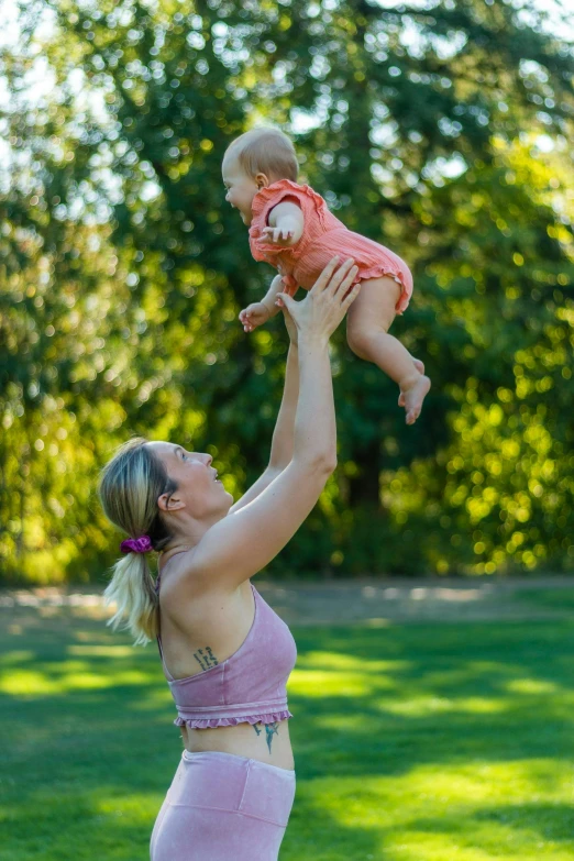 a woman holding a baby up in the air, sydney park, avatar image, square, high quality photo