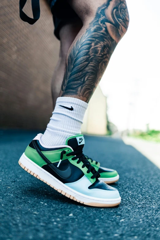 a man with tattoos standing on a skateboard, trending on pexels, nike logo, gradient from green to black, detailed foot shot, stacked