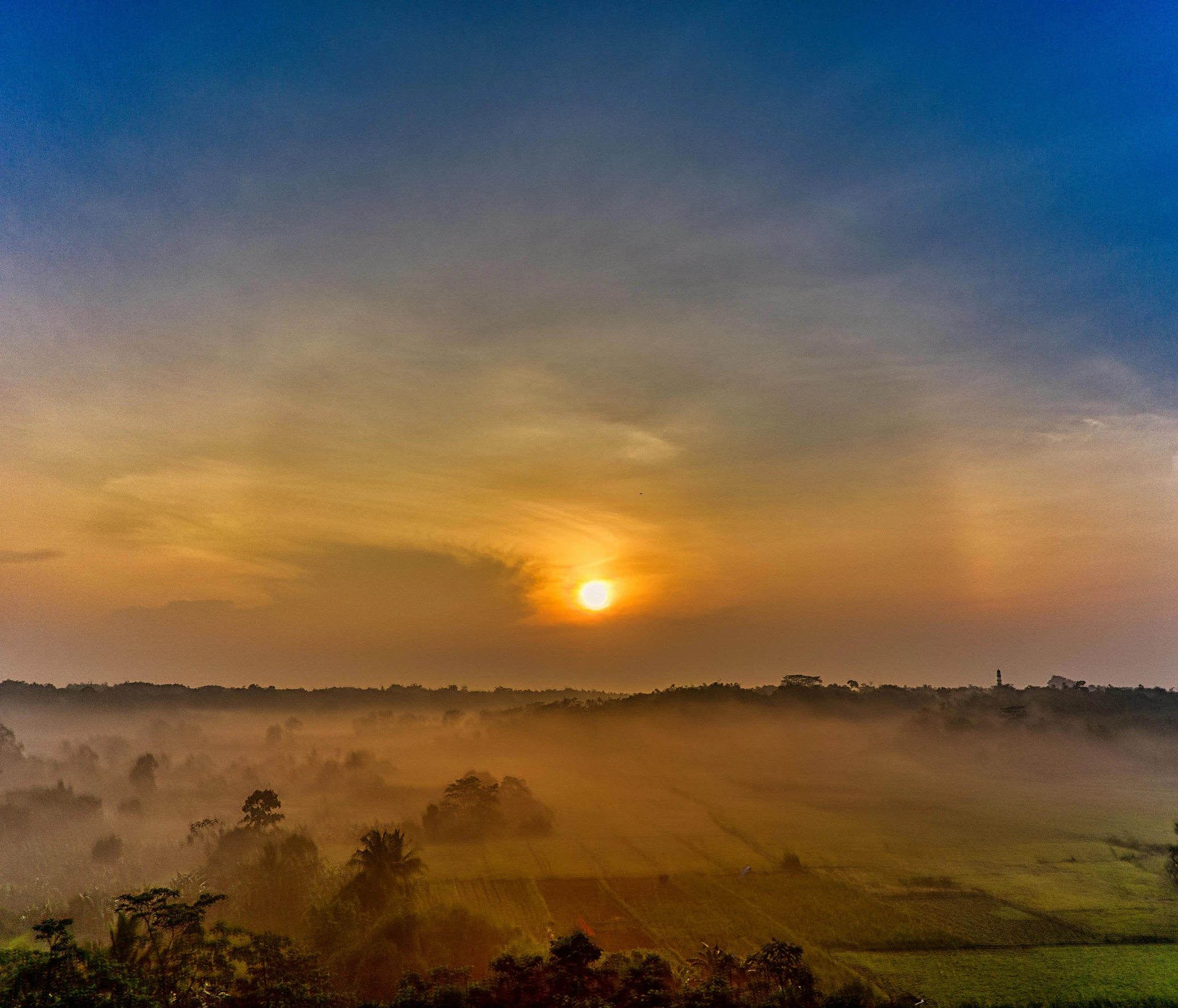 the sun is setting over a foggy field, by Sebastian Spreng, pexels contest winner, sumatraism, panorama view of the sky, sri lankan landscape, high quality image, an ancient