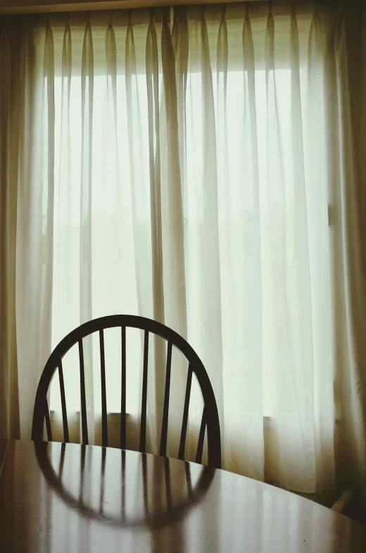 a wooden chair sitting in front of a window, by Elsa Bleda, tonalism, curtain, photograph”, photograph ”