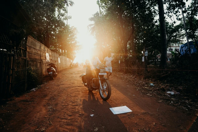 a motorcycle parked on the side of a dirt road, pexels contest winner, happening, streets of mumbai, sun behind her, student, jenna barton