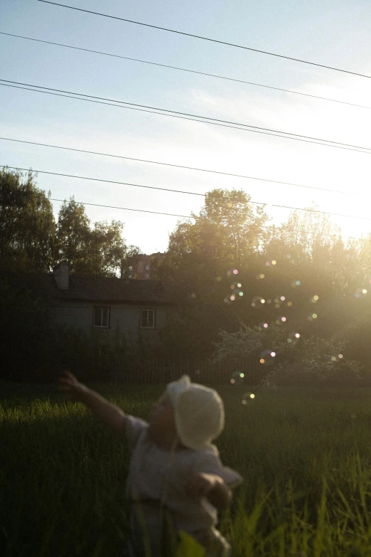 a little girl flying a kite in a field, by Attila Meszlenyi, unsplash, conceptual art, soap bubbles, sunshine through window, in a suburban backyard, medium format. soft light