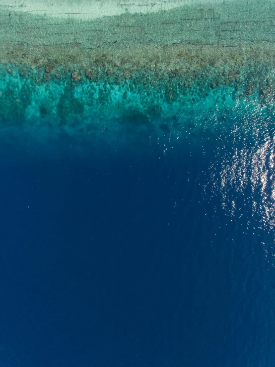 a large body of water next to a sandy shore, an album cover, pexels contest winner, hurufiyya, deep blue ocean color, drone view, maldives in background, official screenshot