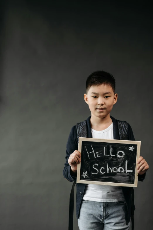 a boy holding a sign that says hello school, pexels, ashcan school, asian male, dark grey backdrop studio, 1 5 6 6, black