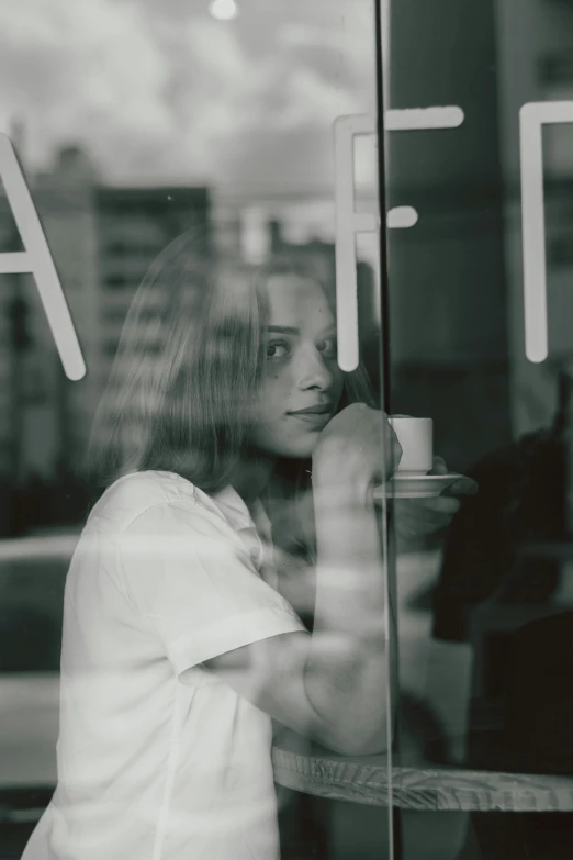 a woman sitting at a table in front of a window, a black and white photo, pexels contest winner, realism, mysterious coffee shop girl, looking in mirror, high quality photo, summer evening