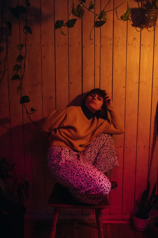 a woman sitting on a stool in a room, an album cover, inspired by Elsa Bleda, trending on pexels, realism, sleepy expression, night outside, yellow carpeted, casual pose