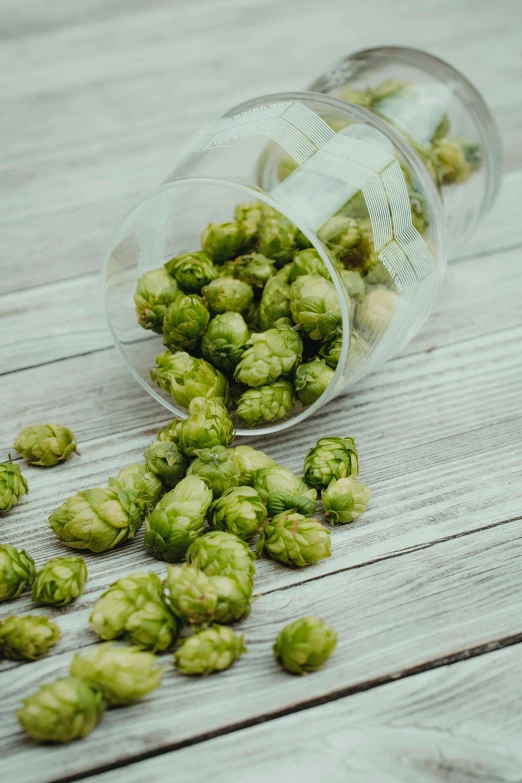 a glass filled with green hops on top of a wooden table, inside a glass jar, thumbnail, snacks, 1 6 x 1 6