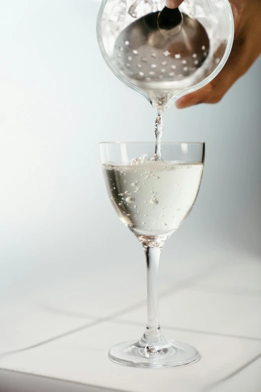 a person pouring a glass of wine into a wine glass, sparkling water, detailed product image, garner holt, tall