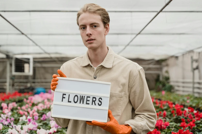 a man holding a sign that says flowers, pexels contest winner, offwhite, joe keery, technical, farms