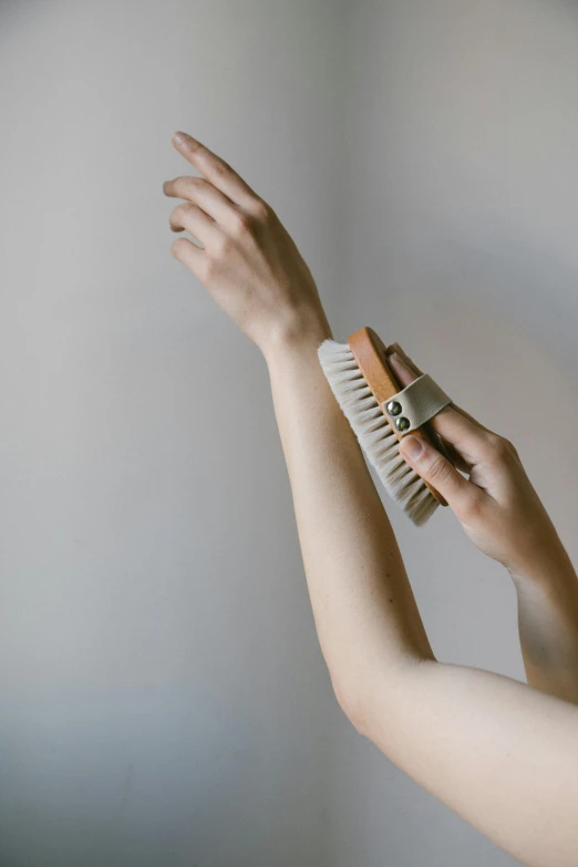 a woman brushing her hair with a brush, an album cover, inspired by Jan Rustem, unsplash, toned arms, sustainable materials, dezeen, accurate hands