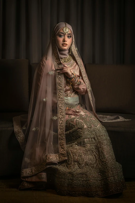 a woman in a bridal sitting on a couch, a colorized photo, by Basuki Abdullah, pexels contest winner, hurufiyya, shot at dark with studio lights, very detailed and rich clothing, intricate details. front on, hindu