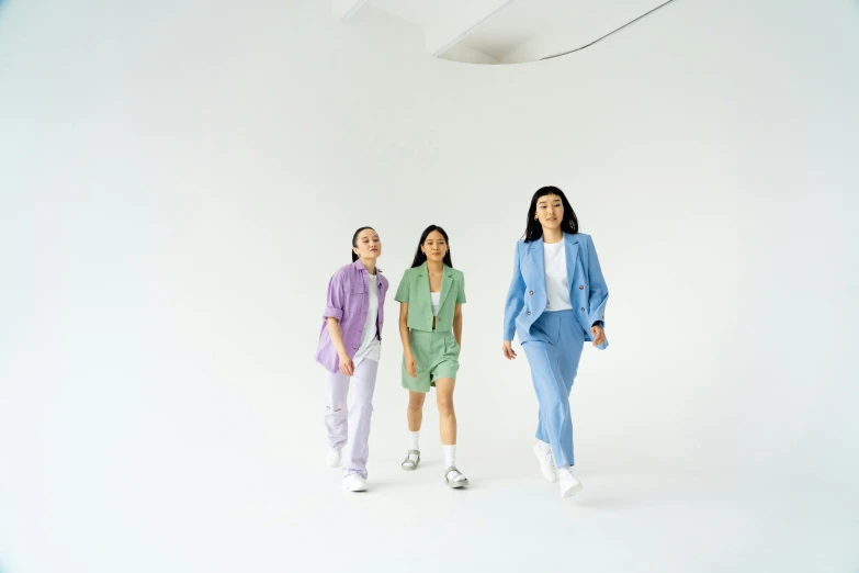 a couple of women standing next to each other, trending on pexels, color field, wearing a light blue suit, three women, wearing white sneakers, blue and purple and green